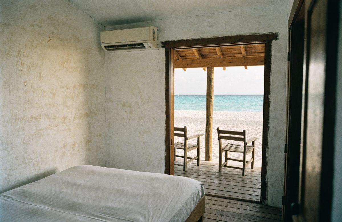 A doorway framing a wooden verandah, palms and the shallow water beyond.